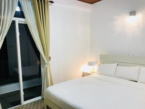 een slaapkamer met een wit bed en een raam bij City Apartment’s Nuwara Eliya in Nuwara Eliya