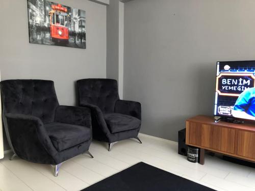 two black chairs in a room with a tv at City center home in Karataş