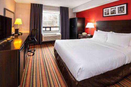 a hotel room with a large bed and a television at Comfort Hotel & Suites in Peterborough