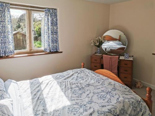 a bedroom with a bed and a mirror and a window at Violet Cottage in Dudbridge