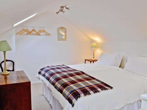Un dormitorio con una cama blanca con una manta. en The Bothy, en Laverton