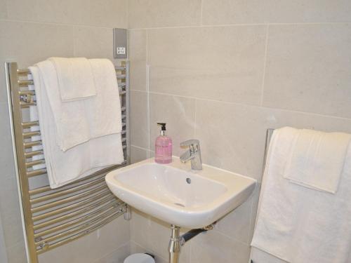 a white bathroom with a sink and towels at The Bothy in Laverton