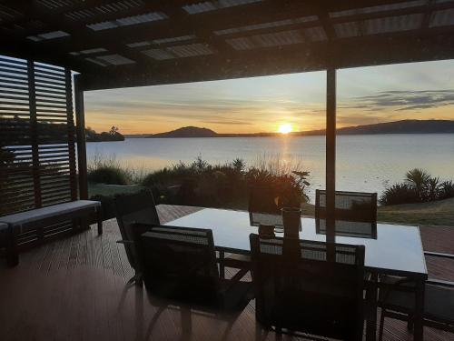 a table and chairs on a patio with a view of a lake at Koutu Beach Bed and Breakfast in Rotorua