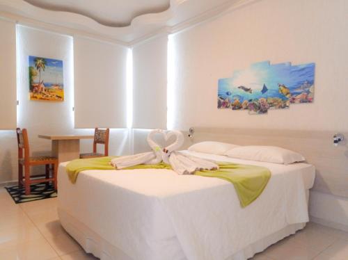 a bedroom with a white bed and a table at Silvestre Praia Hotel in Imbituba