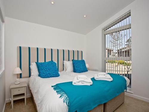 a bedroom with a bed with blue pillows and a window at Una Argentum 61 in Carbis Bay