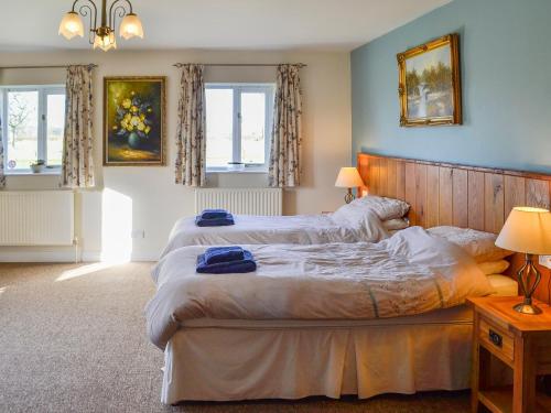 a bedroom with two beds and two windows at Barleycorn in Holwell