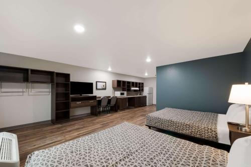 a bedroom with two beds and a desk and a tv at WoodSpring Suites San Antonio UTSA - Medical Center in San Antonio