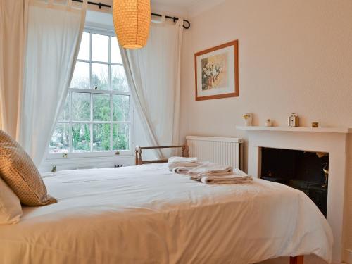 a bedroom with a bed with a fireplace and a window at Daisy Bank Cottage in Bowness-on-Windermere