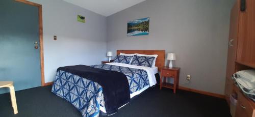 a bedroom with a bed with a blue and white comforter at Koutu Beach Bed and Breakfast in Rotorua