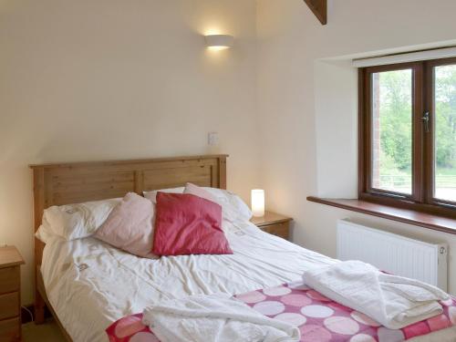 a bed with pink and white pillows and a window at Homeleigh in Poundstock