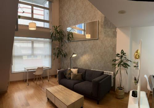 ein Wohnzimmer mit einem Sofa und einem Tisch in der Unterkunft Loft con PARKING "Hygge Urbano Coruña" in A Coruña