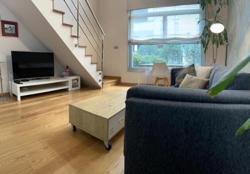 sala de estar con sofá y TV en Loft con PARKING "Hygge Urbano Coruña", en A Coruña