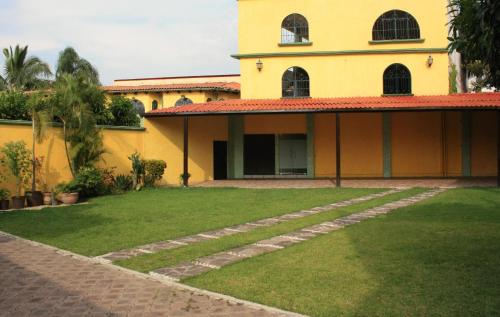 a yellow house with a lawn in front of it at Hotel Oaxtepec in Oaxtepec