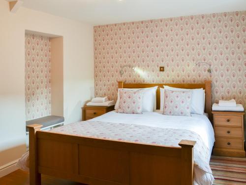 a bedroom with a large bed with pink wallpaper at The Bothy in Bradworthy