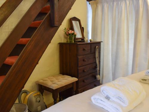 特勞特貝克的住宿－Granary Cottage，一间卧室设有楼梯、一张床和一个梳妆台