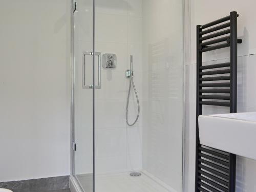 a shower with a glass door next to a sink at Roundhill Cottages 1 in Grasmere