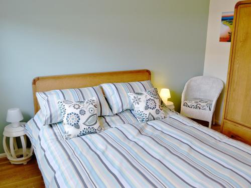 a bed with blue and white sheets and pillows at The Haven in Beadnell