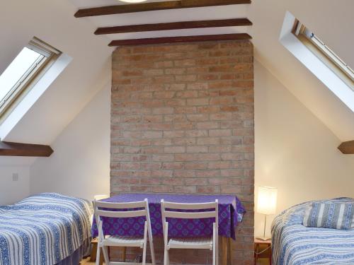 a room with two beds and a table and chairs at Jubilee Cottage in Enstone