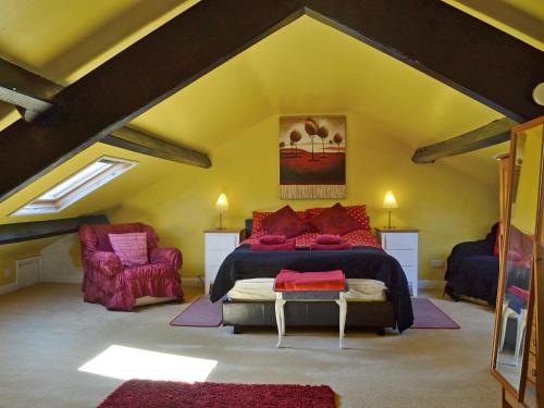 a attic bedroom with a bed and two chairs at Foldgate in Waberthwaite