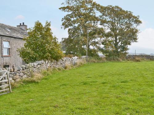 a field next to a stone wall next to a house at Foldgate in Waberthwaite