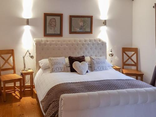 a bedroom with a large white bed with two heart pillows at Summer House Stables in Catfield