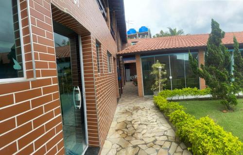 a brick house with a stone walkway next to a building at Colônia Virtual Net in Itanhaém