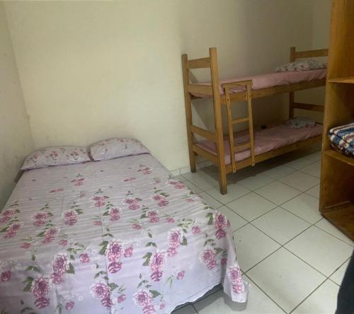 a bedroom with a bed with a pink floral bedspread at Colônia Virtual Net in Itanhaém