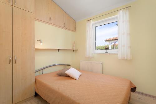 um quarto com uma cama e uma janela em Apartments Ljubica Pulj em Fažana