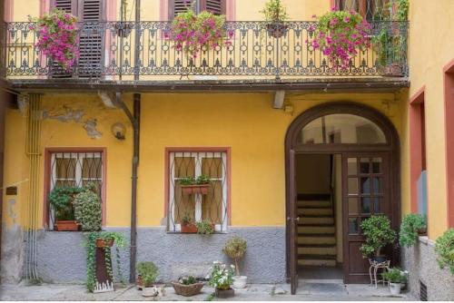 a yellow building with a balcony with flowers on it at Mini suite del borgo antico, design charm centro in Novi Ligure