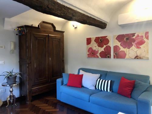 um sofá azul com almofadas vermelhas e brancas numa sala de estar em Mini suite del borgo antico em Novi Ligure