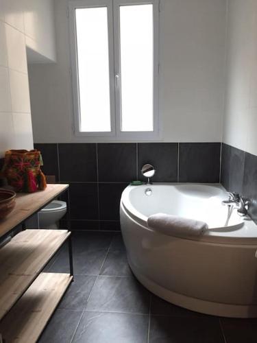 La salle de bains est pourvue d'une baignoire blanche et de 2 fenêtres. dans l'établissement Beautiful studio - 20' walking from Montmartre, à Paris