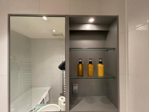 een badkamer met drie flessen op een plank naast een wastafel bij Stunning Westminster Apartment in Londen