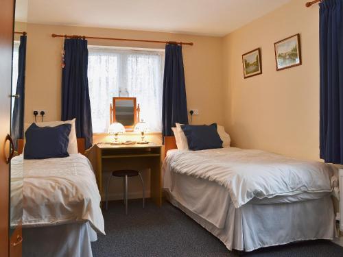 a bedroom with two beds and a desk with a mirror at Swallow Cottage in Llanfair Caereinion