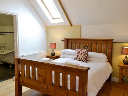 a bedroom with a large wooden bed and a bathroom at White Dove Barn in Wembury