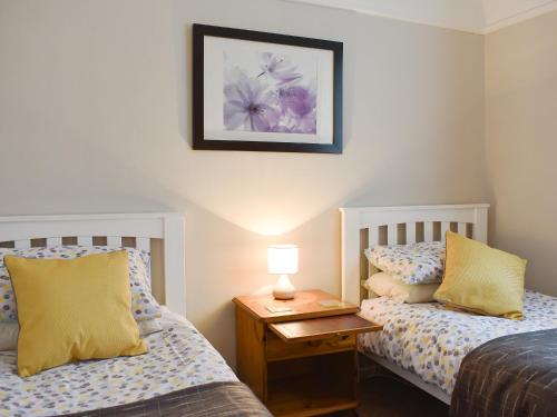 LonghamにあるOak Lodgeのベッドルーム1室(ベッド2台、ランプ付きテーブル付)