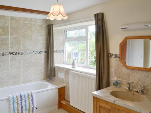 a bathroom with a tub and a sink and a window at The Officers House in Bacton