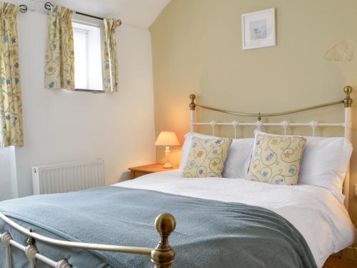 a bedroom with a large bed with a blue blanket at Cross Cottage in Saint Breward