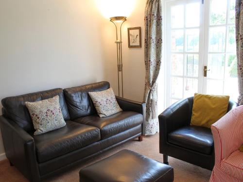 a living room with a leather couch and a chair at Castle House Cottage in Horton