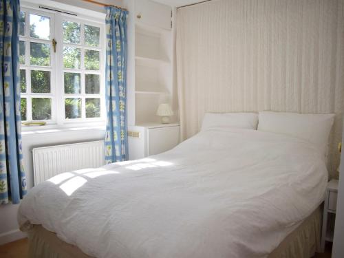 a white bed in a bedroom with a window at Castle House Cottage in Horton