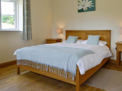 a bedroom with a large bed with blue pillows at Sgubor Ucha in Trefriw