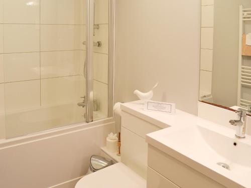 uma casa de banho branca com um lavatório e um chuveiro em Babes Cottage - 27592 em Perranzabuloe