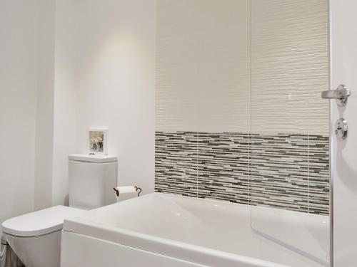 a white bathroom with a tub and a toilet at Abacus in Two Dales