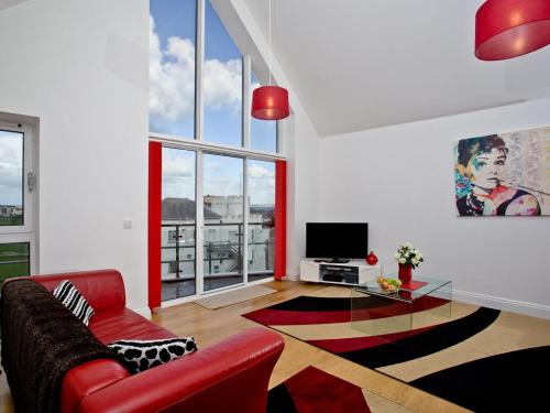 a living room with a red couch and a tv at Bredon Court, Poseidon Penthouse in Newquay
