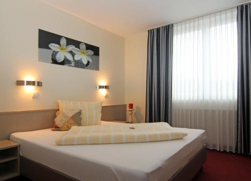 a bedroom with a large white bed with a window at Sporthotel Öhringen in Öhringen