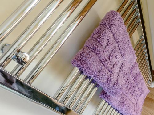 a purple towel hanging on a metal towel rack at Estate Cottage in Wheldrake