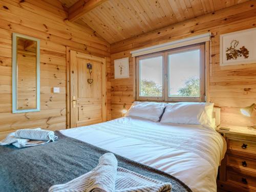 ein Schlafzimmer mit einem Bett in einer Holzhütte in der Unterkunft Buttercup Lodge in Broomhill