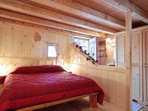 - une chambre dans une cabane en rondins dotée d'un lit rouge dans l'établissement Attractive chalet in Transacqua with garden, à Transacqua