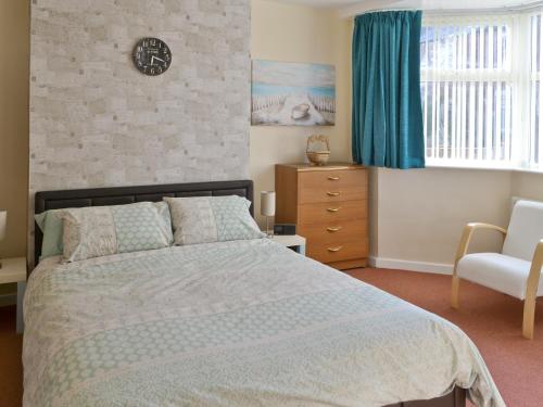 sypialnia z łóżkiem i zegarem na ścianie w obiekcie Seashells w mieście Woodhorn