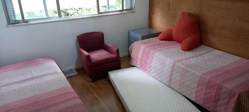 1 dormitorio pequeño con 2 camas y 1 silla en Coração de Ipanema, en Río de Janeiro