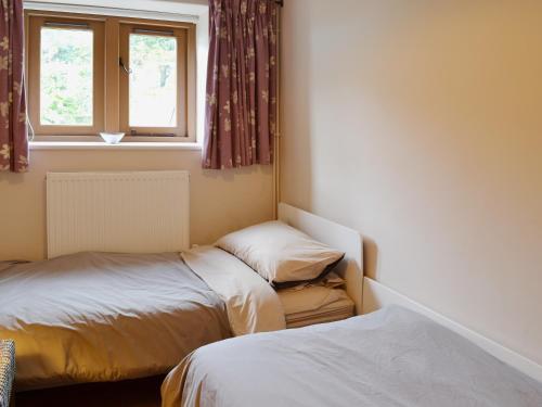 1 dormitorio con 2 camas y ventana en The Threshing Barn en Westbury-sub-Mendip